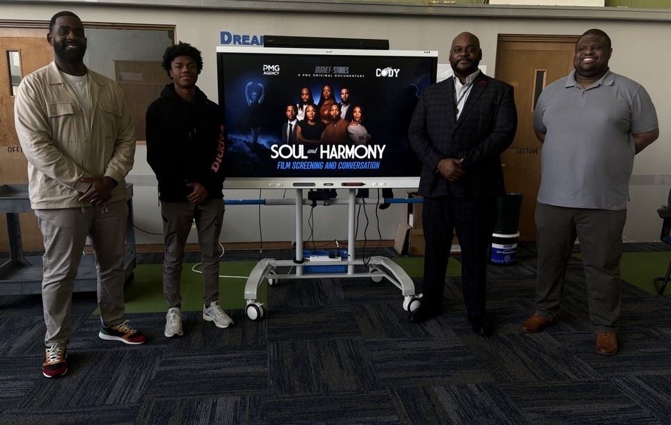  Picture of 4 men standing on either side of smart board with name of film Soul and Harmony on it